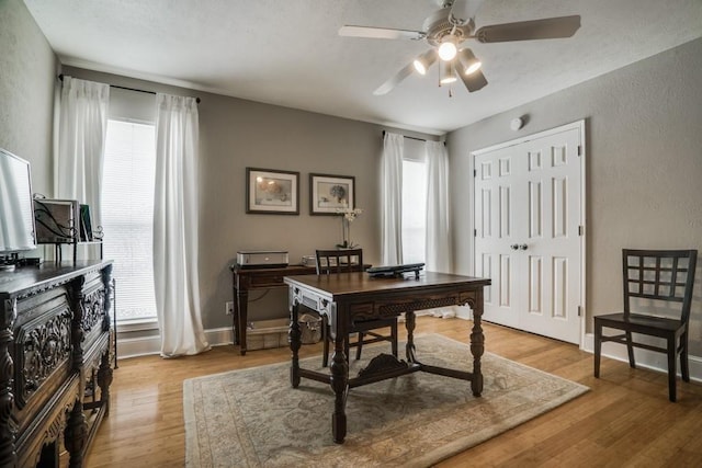 empty room with ceiling fan, light wood finished floors, and baseboards