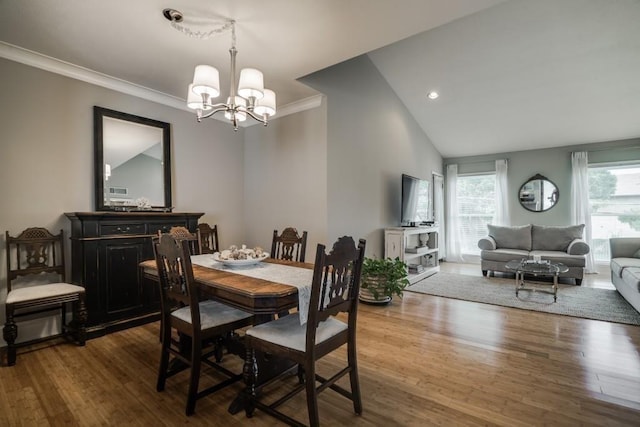 dining area with ornamental molding, a notable chandelier, wood finished floors, and lofted ceiling