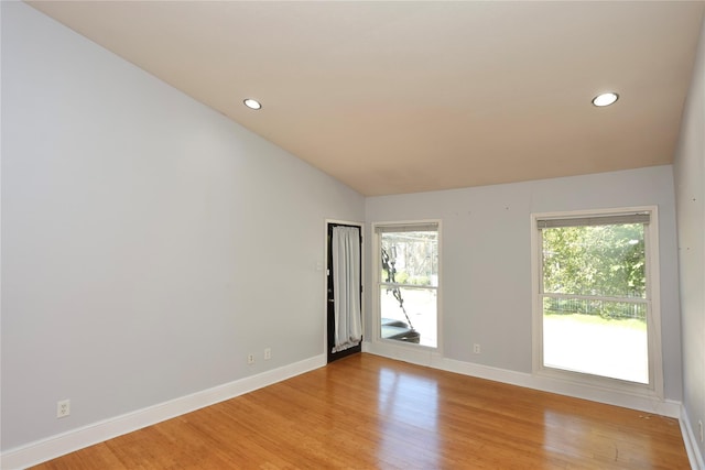 empty room featuring light wood finished floors, recessed lighting, lofted ceiling, and baseboards