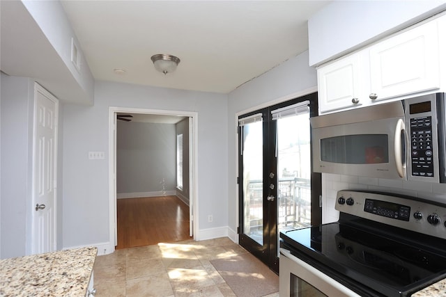 kitchen featuring white cabinets, appliances with stainless steel finishes, french doors, decorative backsplash, and baseboards