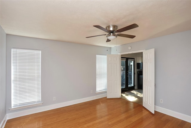 unfurnished bedroom featuring ceiling fan, baseboards, a textured ceiling, and light wood-style flooring