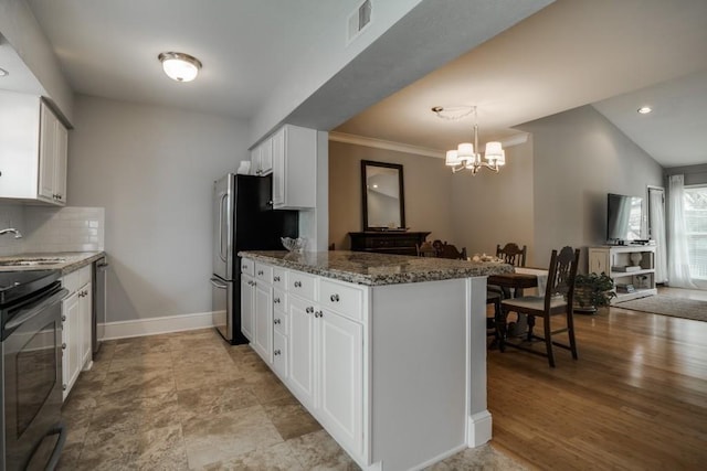 kitchen with stone counters, range, a chandelier, a peninsula, and white cabinetry