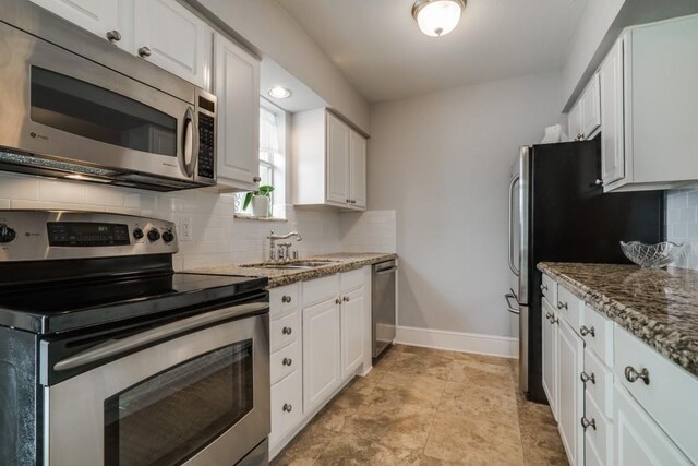 kitchen with white cabinetry, a sink, stainless steel appliances, decorative backsplash, and baseboards