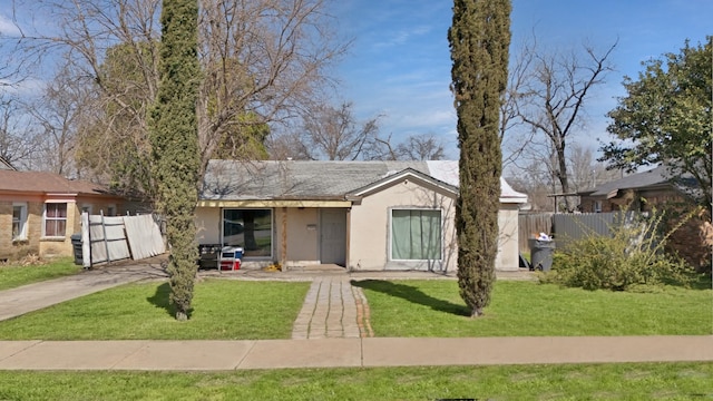 single story home with stucco siding, a front lawn, and fence