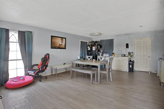 dining room with wood finished floors, baseboards, and a textured ceiling