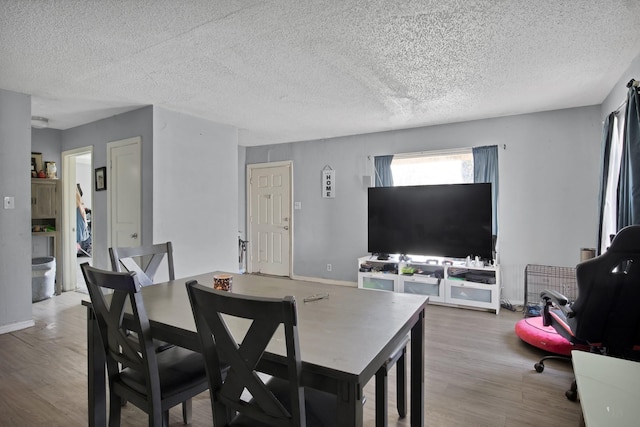 dining room with wood finished floors, baseboards, and a textured ceiling