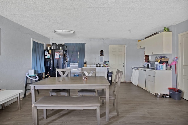 dining area featuring a textured ceiling, dark wood-style floors, and a textured wall