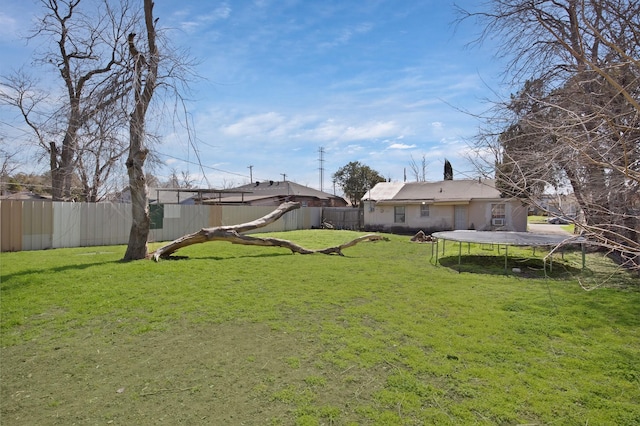 view of yard with a trampoline and a fenced backyard