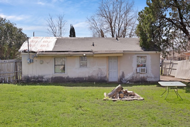 rear view of property featuring stucco siding, a lawn, cooling unit, and fence