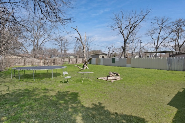 view of yard featuring a fenced backyard, a fire pit, and a trampoline