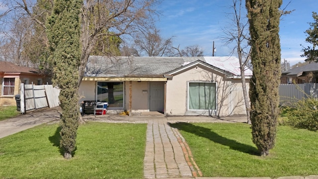 view of front of property featuring stucco siding, a front yard, and fence