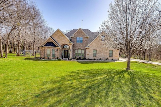 view of front facade featuring brick siding, a front yard, and fence