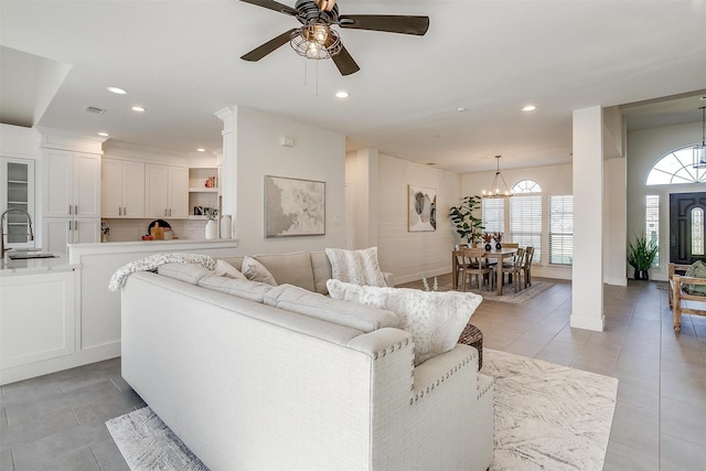 living room with light tile patterned flooring, visible vents, recessed lighting, and ceiling fan with notable chandelier