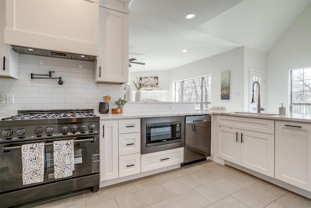 kitchen featuring appliances with stainless steel finishes, white cabinetry, wall chimney exhaust hood, and a sink