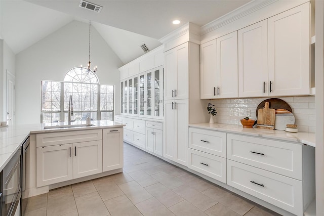 kitchen with visible vents, glass insert cabinets, a chandelier, white cabinets, and a sink