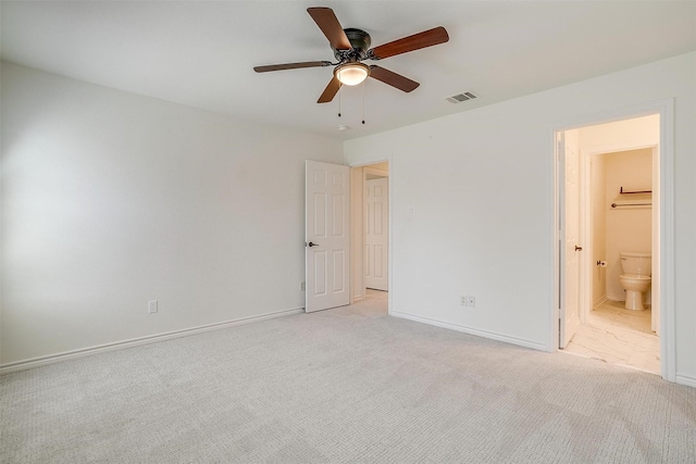 unfurnished bedroom featuring visible vents, baseboards, light colored carpet, ensuite bathroom, and a ceiling fan