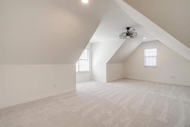 additional living space featuring light carpet, ceiling fan, lofted ceiling, and baseboards