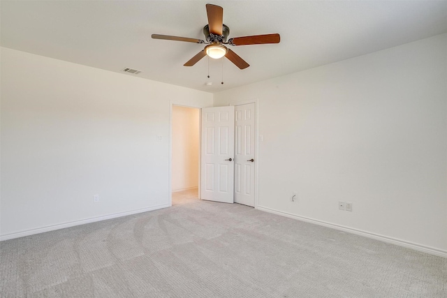 empty room with baseboards, light carpet, visible vents, and a ceiling fan