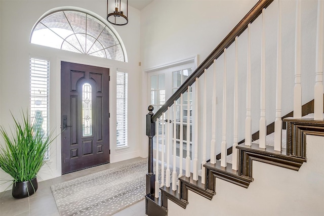 entrance foyer with tile patterned floors, a high ceiling, and stairs