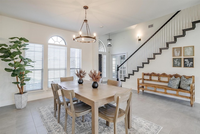 tiled dining room with stairway, baseboards, visible vents, and a chandelier