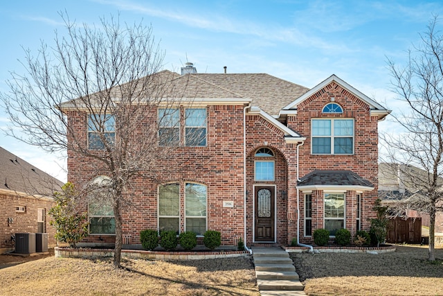 traditional-style home featuring brick siding, roof with shingles, a chimney, and fence