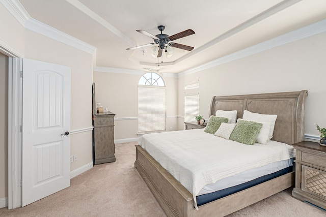 bedroom featuring baseboards, a tray ceiling, ornamental molding, light carpet, and a ceiling fan