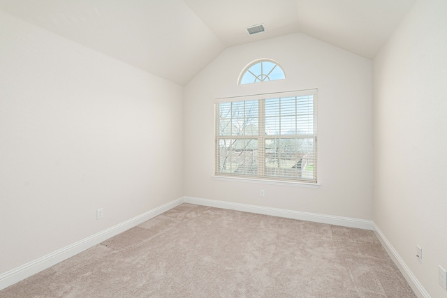 spare room featuring visible vents, carpet flooring, baseboards, and lofted ceiling