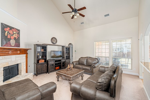 living room with light colored carpet, a stone fireplace, ceiling fan, and high vaulted ceiling