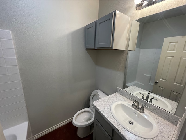 full bathroom with vanity, a bath, baseboards, toilet, and a textured wall