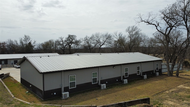 back of house with central air condition unit and metal roof