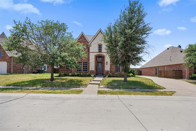 view of front of house with brick siding, a front lawn, and fence