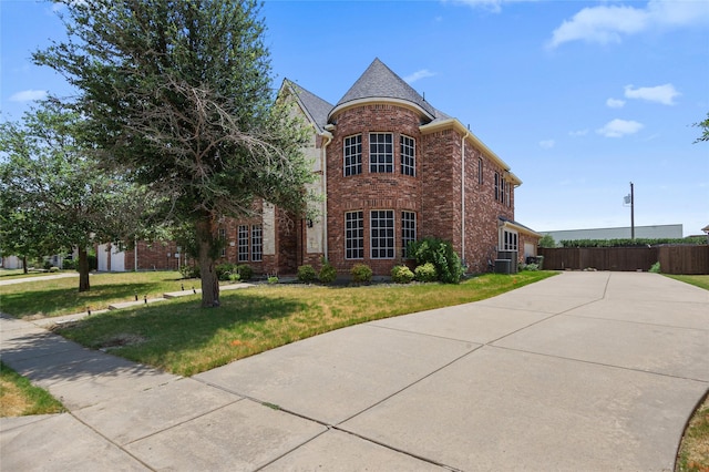 traditional home featuring brick siding, a front yard, and fence