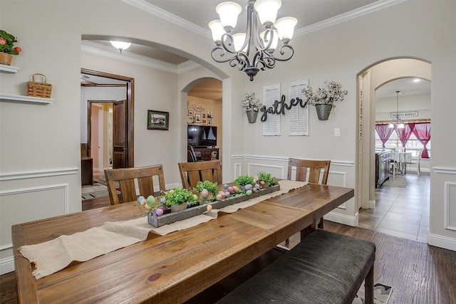 dining space with arched walkways, a notable chandelier, wainscoting, and a decorative wall