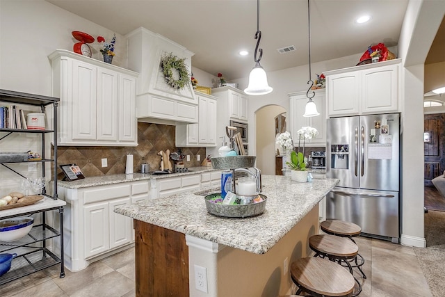 kitchen featuring visible vents, arched walkways, white cabinets, appliances with stainless steel finishes, and backsplash