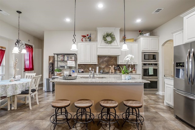 kitchen with visible vents, a breakfast bar, appliances with stainless steel finishes, white cabinetry, and tasteful backsplash