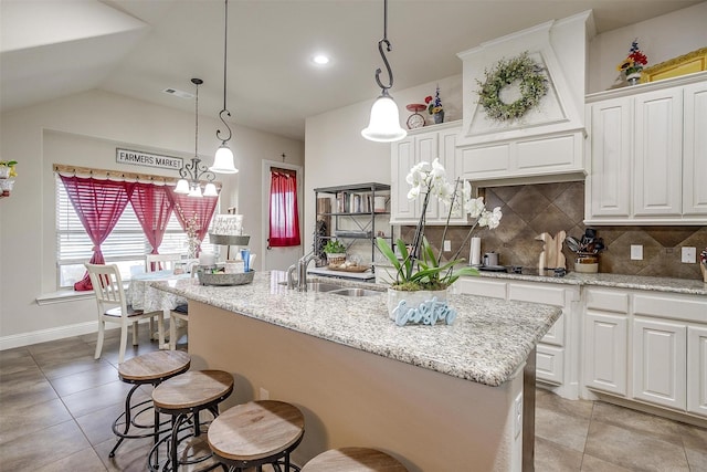 kitchen with visible vents, tasteful backsplash, a breakfast bar area, white cabinets, and light stone countertops