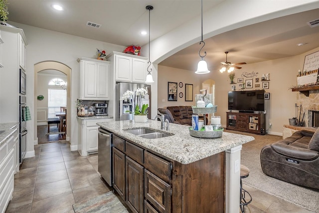 kitchen featuring arched walkways, open floor plan, visible vents, and a sink