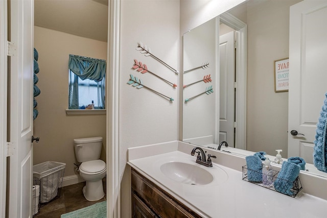 bathroom featuring toilet, vanity, and baseboards