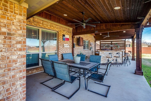 view of patio / terrace with outdoor dry bar, outdoor dining space, and a ceiling fan