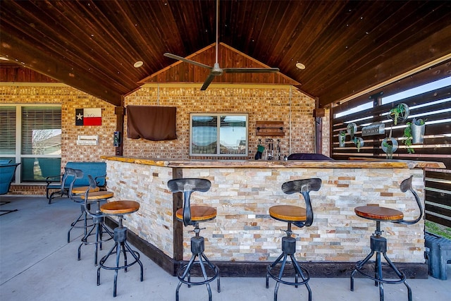 bar with vaulted ceiling, brick wall, wood ceiling, and concrete flooring