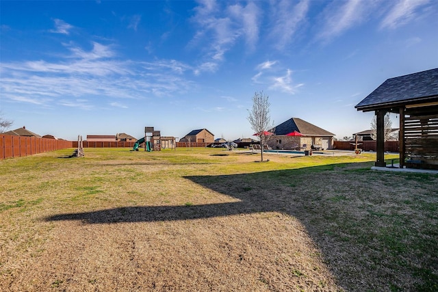 view of yard featuring playground community, a patio, a fenced in pool, and fence