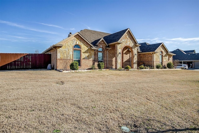 view of front facade featuring brick siding and fence