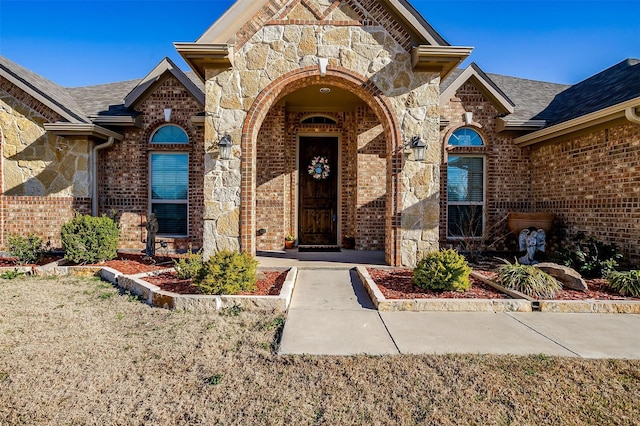 entrance to property featuring stone siding and brick siding