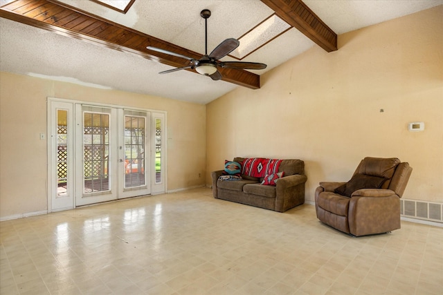 living area featuring tile patterned floors, visible vents, lofted ceiling with skylight, baseboards, and ceiling fan