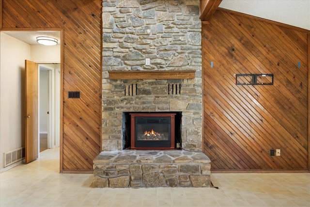 room details with a stone fireplace, visible vents, and wood walls