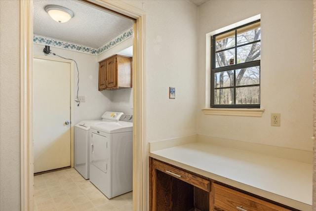 laundry area featuring washing machine and dryer, cabinet space, light floors, and a textured ceiling