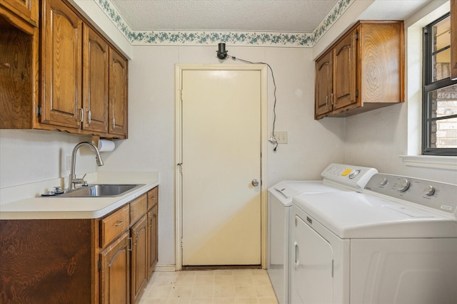 clothes washing area with a sink, cabinet space, separate washer and dryer, and a textured ceiling