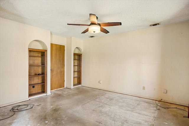 spare room featuring visible vents, concrete floors, ceiling fan, arched walkways, and a textured ceiling