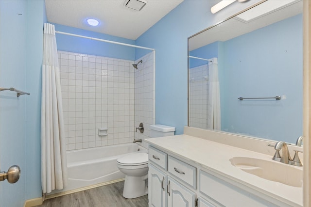 full bath with toilet, shower / bath combo with shower curtain, wood finished floors, a textured ceiling, and vanity