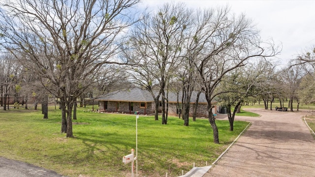 view of front of property with stone siding, driveway, and a front yard